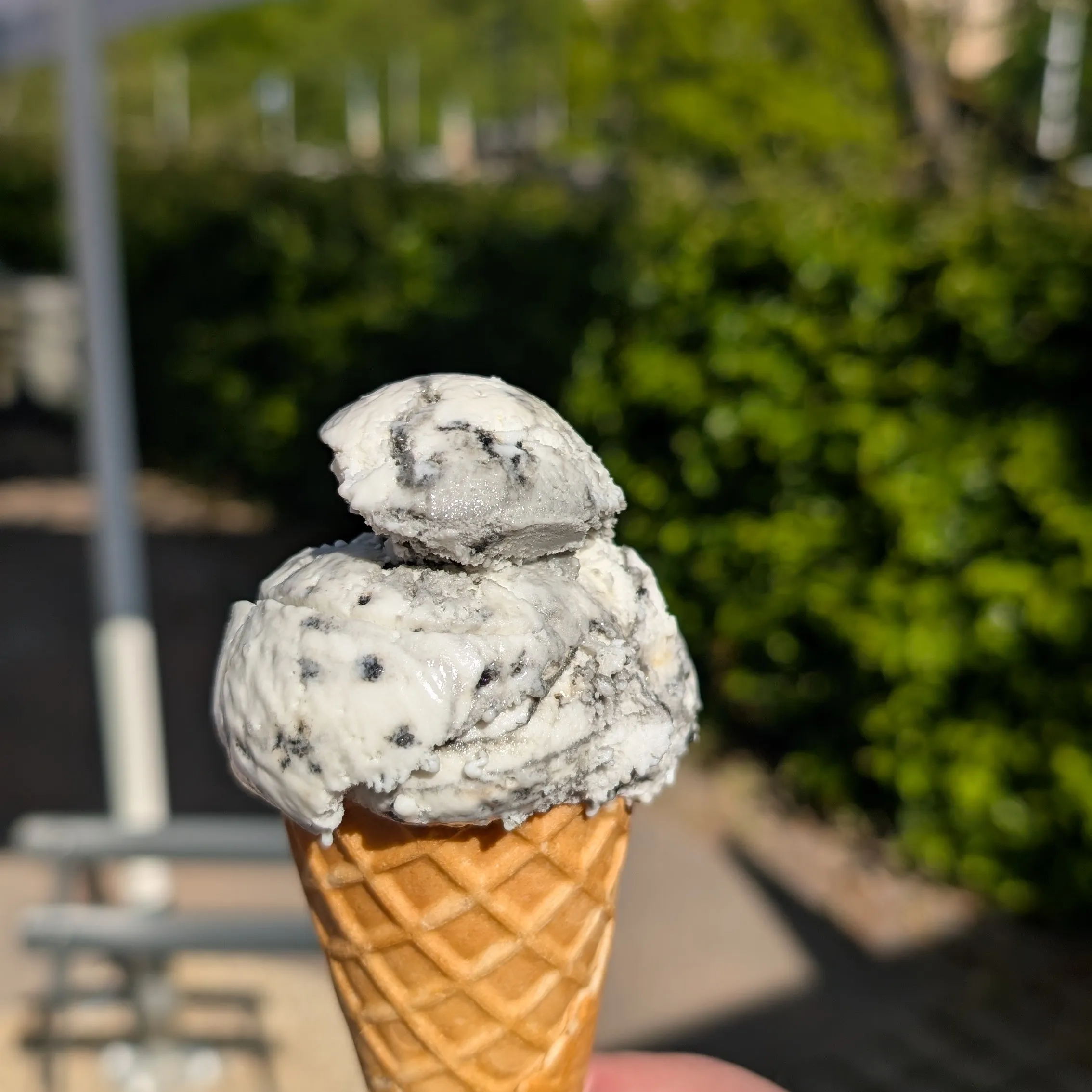 Lähikuva jäätelötötteröstä, jossa valkoista vaniljajäätelöä ja mustia salmiakkiraitoja.